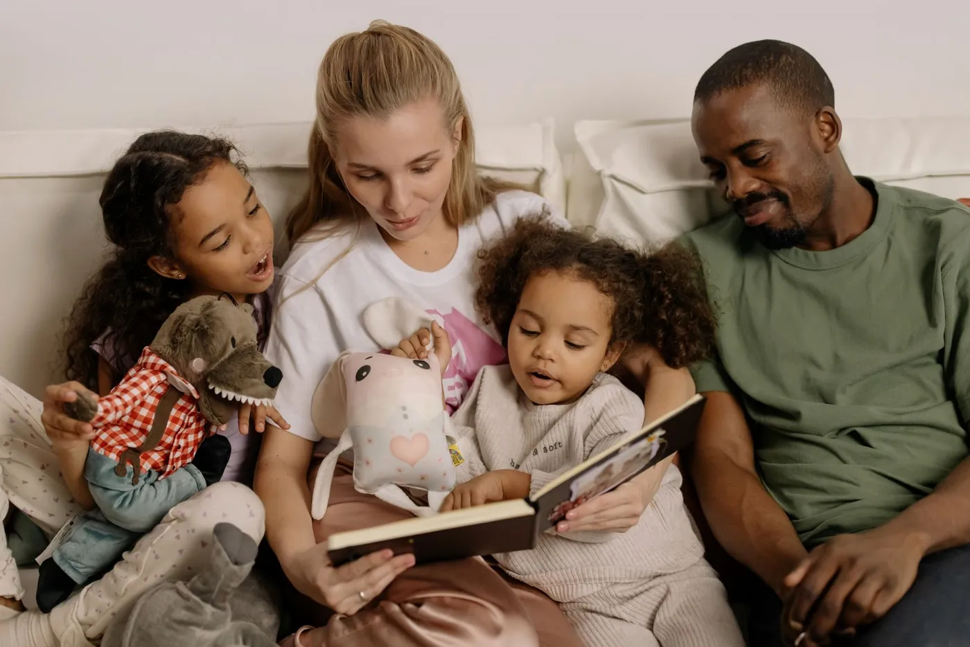 Eltern lesen mit zwei Kindern gemeinsam ein Buch