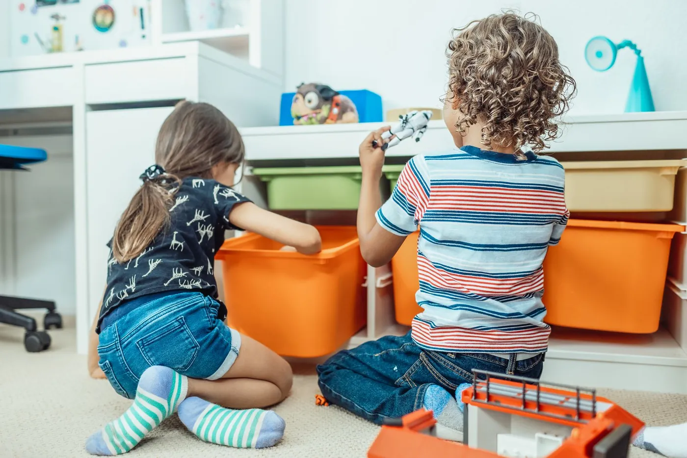 Zwei Kinder räumen gemeinsam ihr Spielzimmer auf